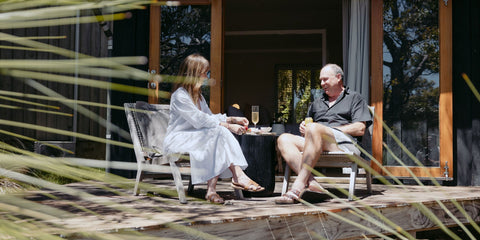 Man and woman sitting on a wooden deck with a scenic background