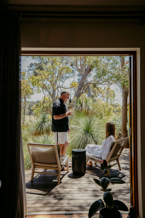 Two people drinking champagne on a wooden deck with trees in the background