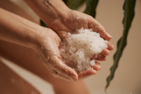 Hands holding salt with rose petals with leaf neutral background