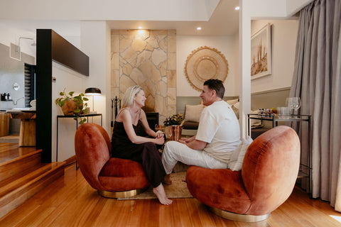 Two people sitting on a modern, curved brown sofa in a stylish living room.