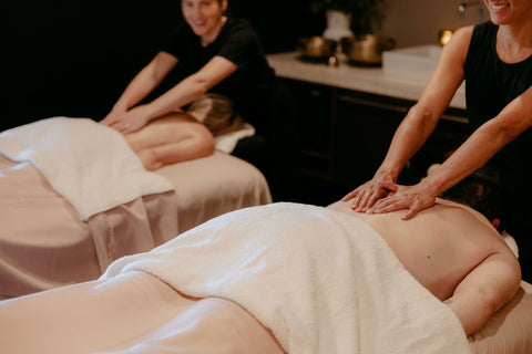 Two masseuses providing massages to clients in a spa setting.