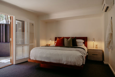 Modern bedroom with a bed, nightstands, and open door leading to a balcony.
