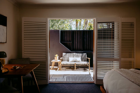 Living room with a view of a patio area through open shutters