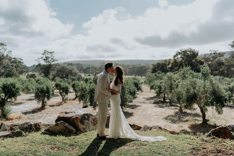 Couple kissing at their wedding in an olive grove with a scenic background