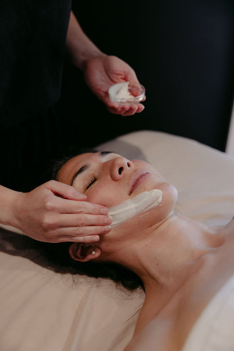 Person receiving a facial treatment with a white cream on a blurred background