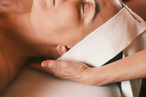 Close-up of a person receiving a facial massage with a white towel on their face.