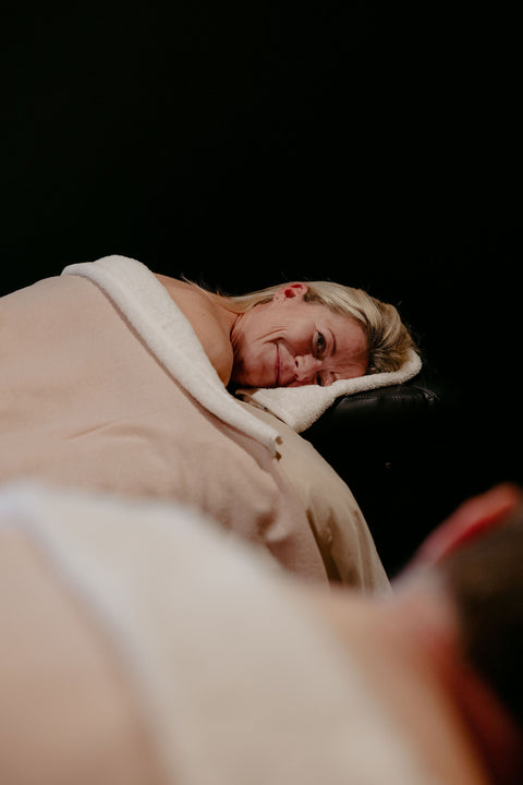 Person wrapped in a beige blanket with a black background