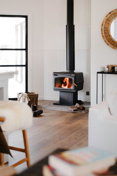 Modern living room with a wood stove, white walls, and wooden floor.