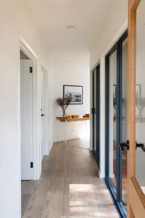 Modern interior hallway with wooden flooring, white walls, and a console table.