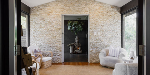 Modern interior with stone wall, white furniture, and a statue.