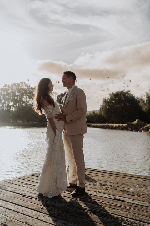 Couple on dock in wedding dress with birds in background celebrating