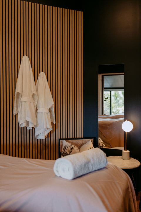 Bedroom with a bed, pillows, and a lamp next to a striped wall.