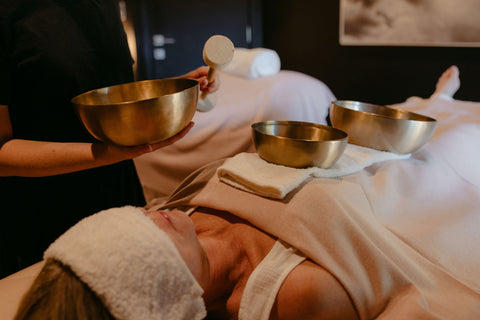 Person receiving a sound therapy session with sound bowls on a table