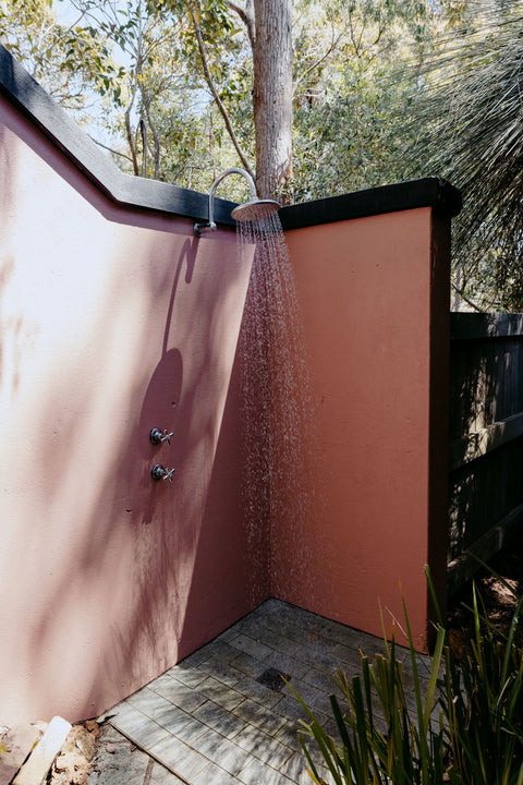 Outdoor shower with water flowing, surrounded by trees and natural light
