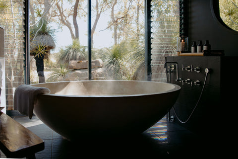 Modern bathroom with a freestanding bathtub and large windows overlooking nature.